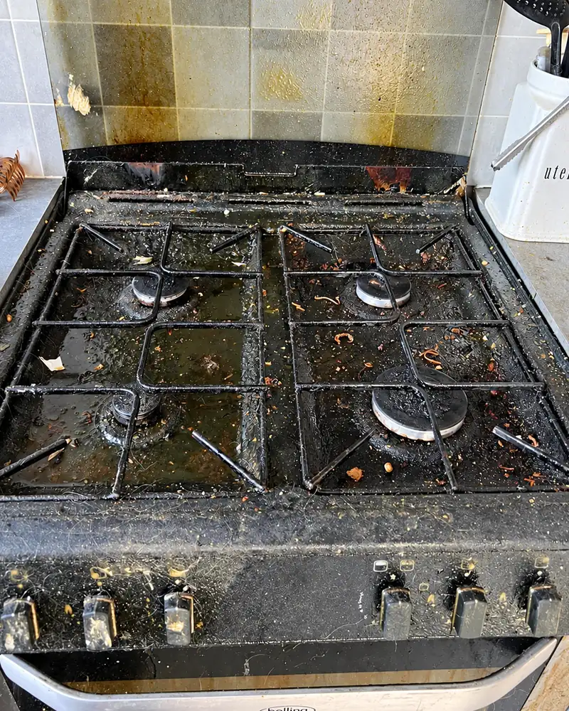 Belling gas hob before cleaning, with the hob top and pan supports caked in grease, burnt food and crumbs